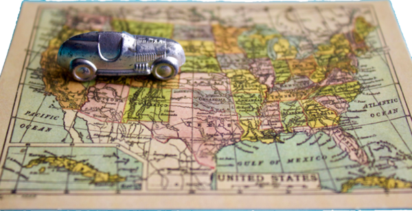 Little silver car riding over paper map of the United States.